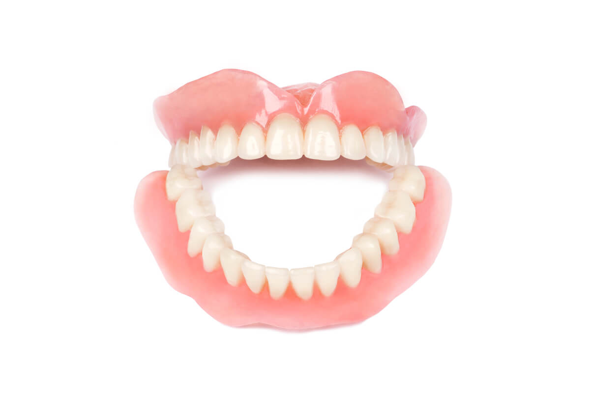 Affordable Full Dentures - A close-up image of a set of full dentures, showcasing both the upper and lower arches of artificial teeth. The dentures are made with a pink gum-like base, mimicking the natural appearance of gums, and white teeth that are carefully aligned to provide a natural-looking smile. The image, set against a plain white background, emphasizes the accessibility and affordability of full dentures as a solution for individuals who have lost all of their natural teeth. The clean and simple presentation highlights the dentures as a cost-effective option for restoring dental function and improving oral aesthetics.