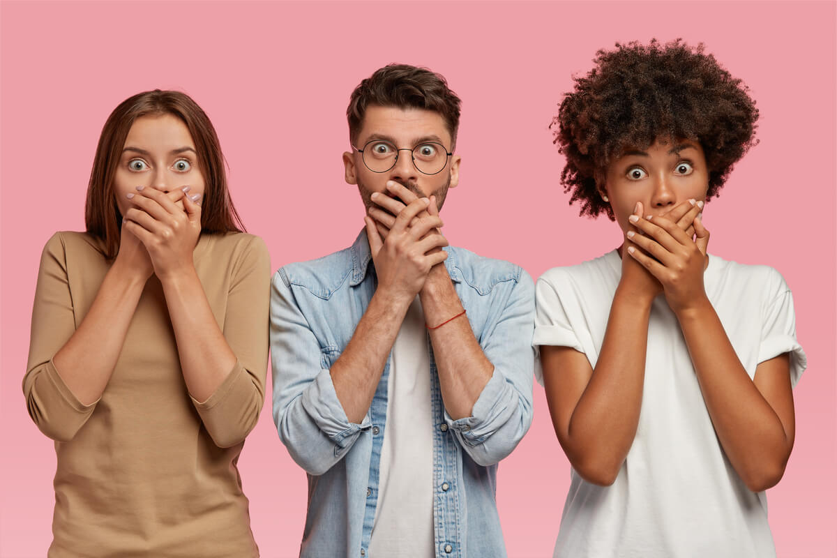 How to Treat Bad Breath (Halitosis) - Three individuals, two women and one man, stand in front of a solid pink background with their hands covering their mouths, appearing shocked or surprised. This visual representation could symbolize the common reaction to bad breath, emphasizing the social discomfort associated with halitosis. The image highlights the importance of addressing bad breath, a condition often caused by poor oral hygiene, certain foods, or underlying health issues. Effective treatments include regular brushing, flossing, and using mouthwash, along with seeking professional dental care when necessary.