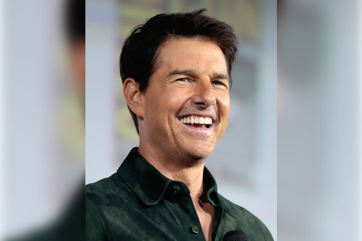 5 Celebrity Smiles - A well-known actor is showcasing a radiant smile at a public event. His teeth are perfectly aligned and gleaming, exemplifying the kind of smile that captures attention on the red carpet. Dressed in a casual green shirt, he appears to be in high spirits, holding a microphone, likely addressing the audience. The setting suggests a formal gathering or press conference, with blurred background elements typical of a stage or panel discussion. This image highlights the actor's charisma and the importance of maintaining a bright, healthy smile in the entertainment industry.